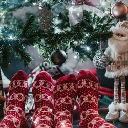 Two sets stockinged feet under a Christmas tree Photo by Arthur Brognoli Pexels