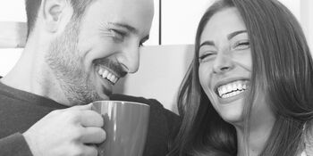 Couple sitting drinking from mugs and laughing Photo Thinkstock